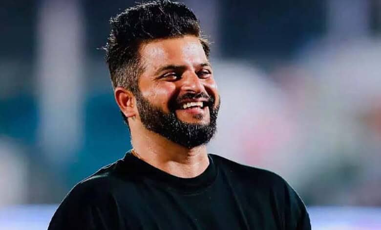 Smiling man with a beard and short hair in a black shirt outdoors.