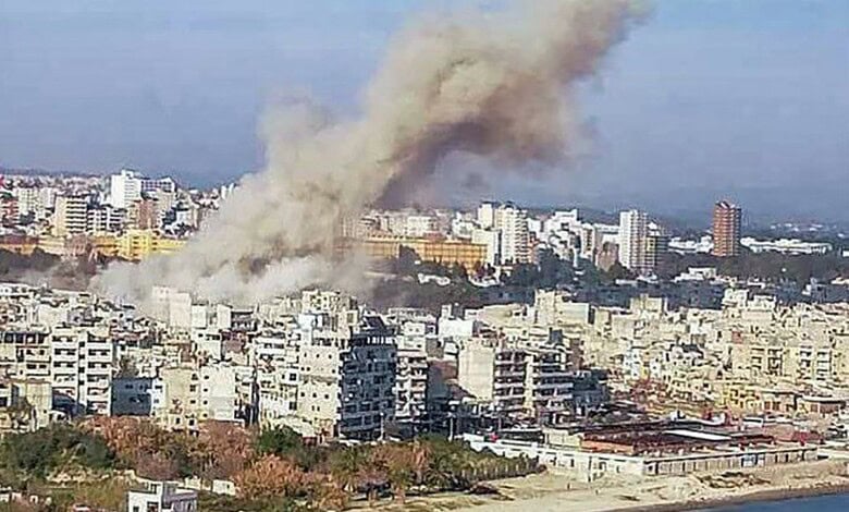 Smoke rises over a city after a devastating ordnance blast in Syria, causing casualties and destruction.