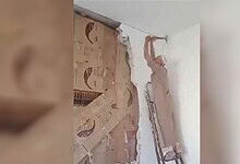 Man breaking wall to reveal a secret library behind it in Syria.