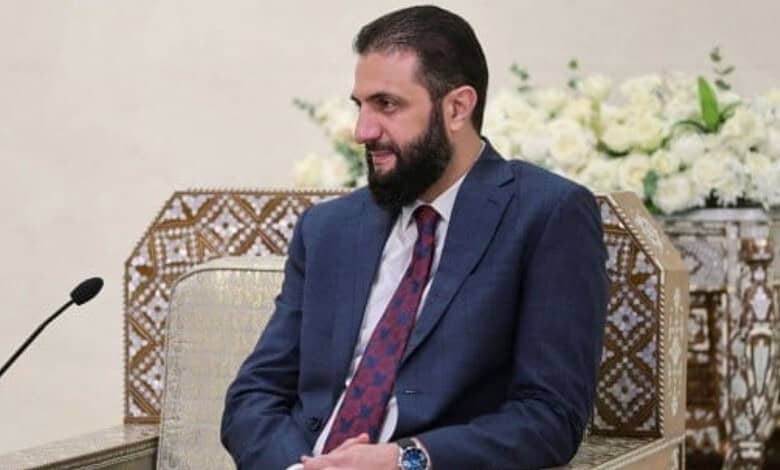 Syrian president with beard in a blue suit during a formal meeting.