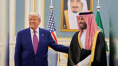 President Trump and Saudi official smiling during diplomatic meeting in ornate room.
