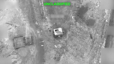 Aerial image showing a small building surrounded by open land and sparse vegetation.