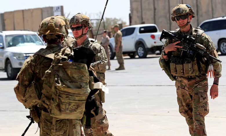 US troops in military gear standing near vehicles in Iraq.