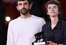 Two filmmakers, one holding a trophy, pose at an event in Gaza.