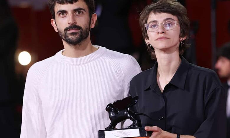 Two filmmakers, one holding a trophy, pose at an event in Gaza.