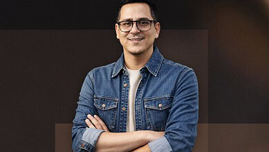 Indian-origin filmmaker Arafat Sheikh smiling with crossed arms in a denim jacket.