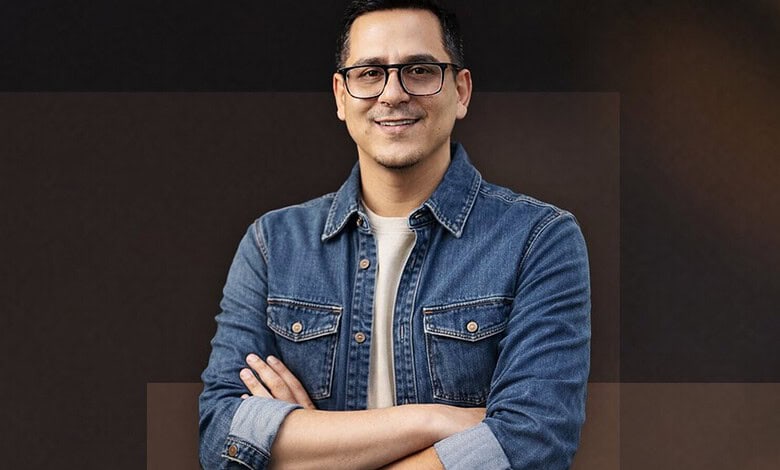 Indian-origin filmmaker Arafat Sheikh smiling with crossed arms in a denim jacket.
