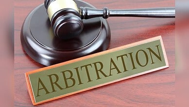 Gavel and arbitration sign on wooden desk, legal dispute resolution concept.