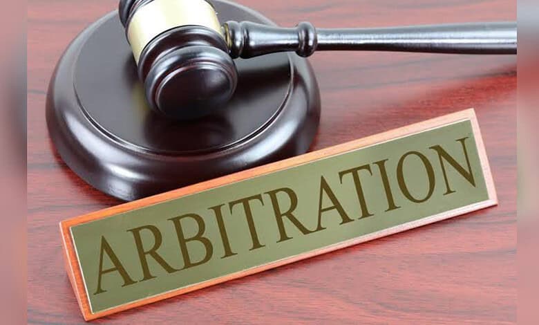 Gavel and arbitration sign on wooden desk, legal dispute resolution concept.