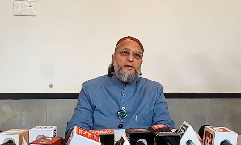 Elderly man in blue kurta speaking at a press conference with microphones.