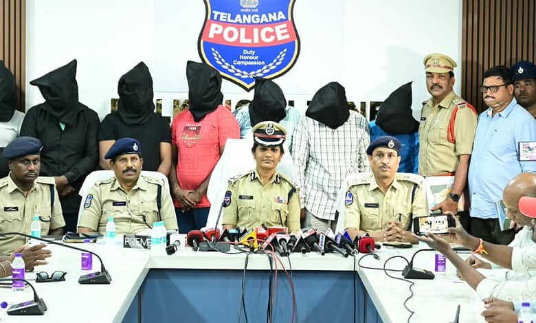 Seven suspects with covered faces and police officers during a press conference in Telangana.