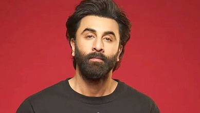 Portrait of a man with a beard and black hair against a red background.
