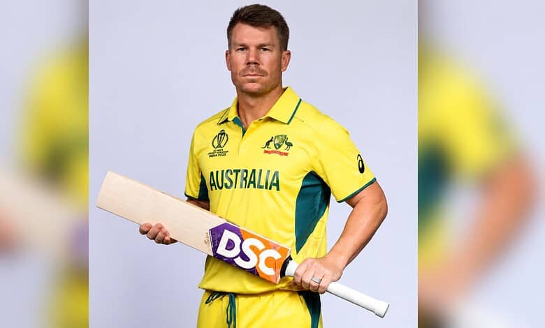 Australian cricket player in yellow uniform holding a cricket bat.