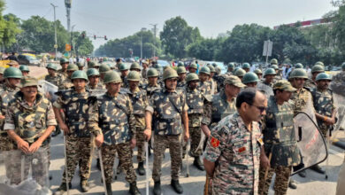 Indian police and military personnel in uniform at a protest site in Delhi.