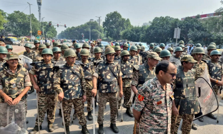 Indian police and military personnel in uniform at a protest site in Delhi.