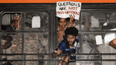 Protesters inside a bus holding a sign that questions anti-national sentiments.