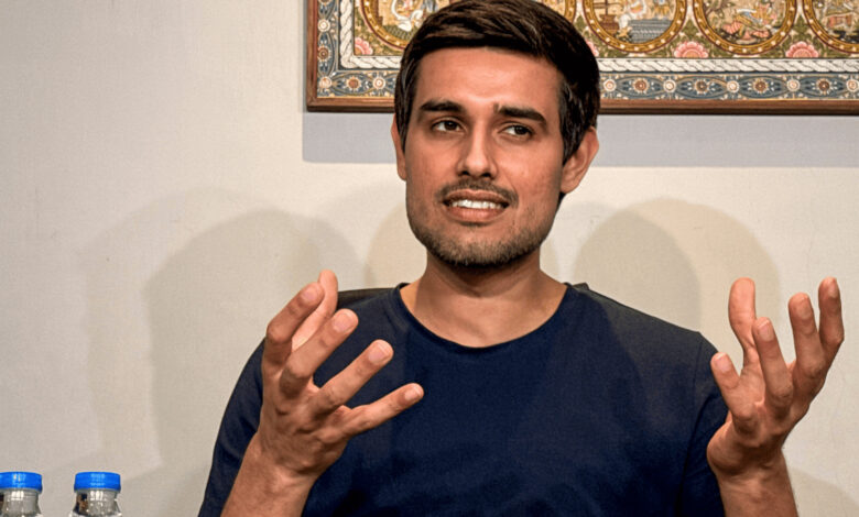 Dhruv Rathee speaking passionately with hand gestures in an indoor setting.