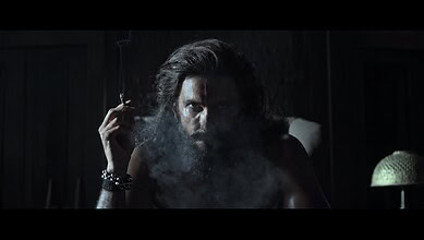 Ranveer Singh as Dhurandhar in a dark scene with smoke and intense expression.