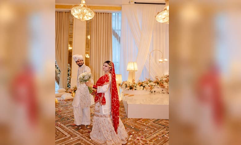 Bride and groom at wedding reception in elegant traditional attire, decorated venue.