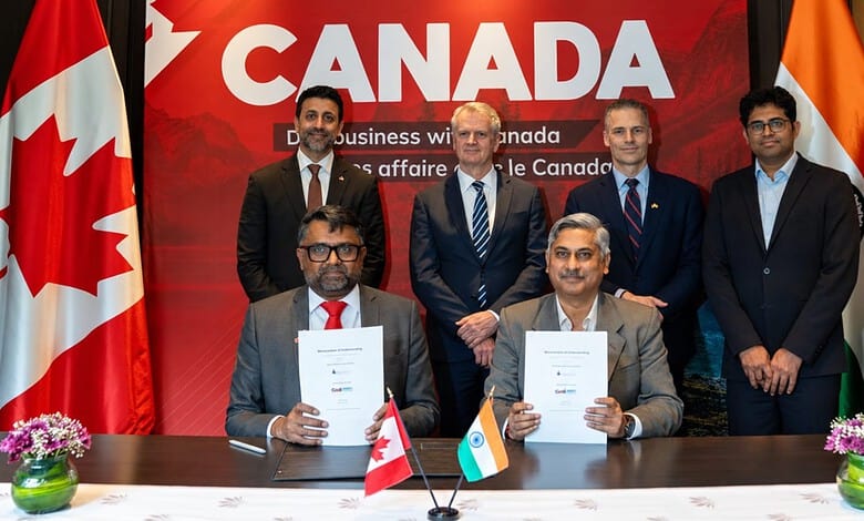 Business leaders from Canada and India sign agreements at a formal event with flags and a 'Canada' banner.