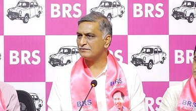 Telangana politician speaking at BRS event with pink and white backdrop.