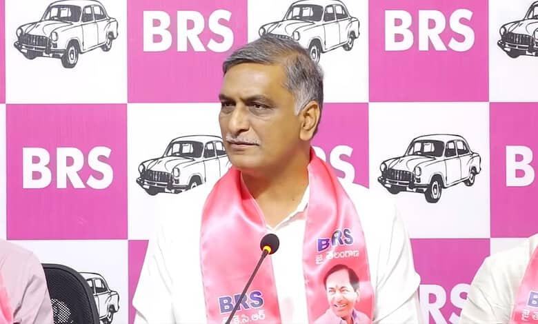Telangana politician speaking at BRS event with pink and white backdrop.