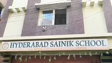 Hyderabad Sainik School building with school sign and decorative hanging ornaments.