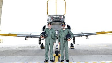 Indian Air Force pilots in green flight suits standing in front of a fighter jet at Hyderabad airbase.