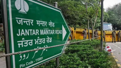 Jantar Mantar Road sign in Delhi with police and barricades nearby.