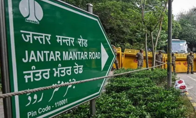 Jantar Mantar Road sign in Delhi with police and barricades nearby.