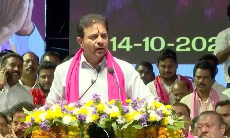 KTR speaking at a public event with a floral arrangement in front, surrounded by supporters.