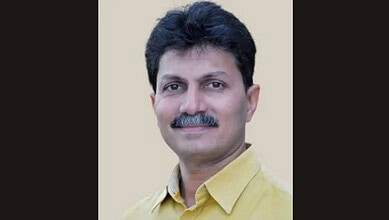 Portrait of Ravi Patil, smiling, wearing a yellow shirt, against a plain background.