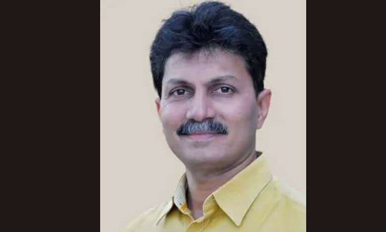 Portrait of Ravi Patil, smiling, wearing a yellow shirt, against a plain background.