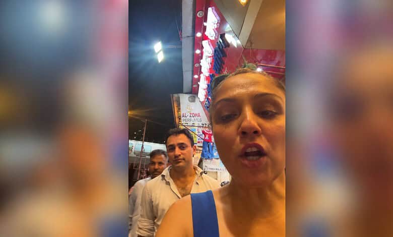 A woman taking a selfie with Imran Khan in the background at a political rally.