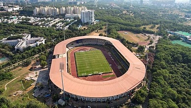 Gachibowli Stadium with lush greenery and cityscape in the background.