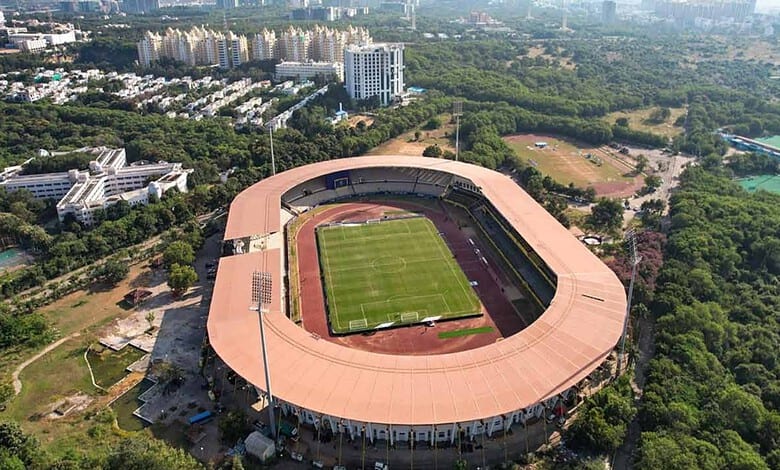 Gachibowli Stadium with lush greenery and cityscape in the background.