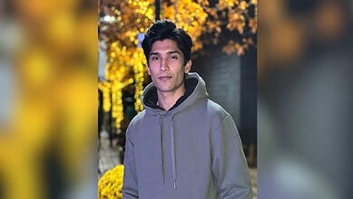 Pakistani cricketer Mohammad Hasnain in a grey hoodie outdoors during autumn.