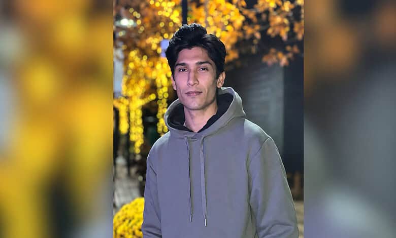Pakistani cricketer Mohammad Hasnain in a grey hoodie outdoors during autumn.