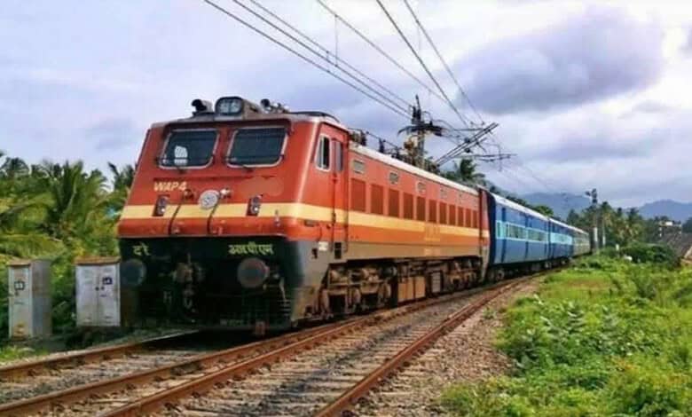 Passenger train moving through lush green landscape near Mysuru during daytime.