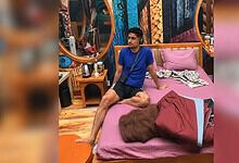 Nakul Dhull sitting on a pink bed in a room with colourful decor and mirrors.