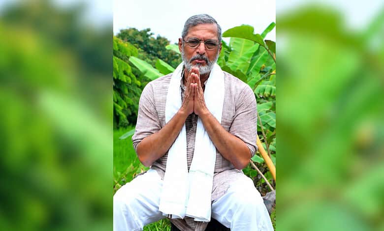 Nana Patekar praying outdoors with greenery in the background.