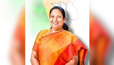 Sudha Yadav smiling in traditional orange saree during swearing-in as Karnataka Governor.