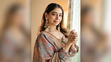 Niti Taylor wearing traditional Indian dress with jewelry, smiling softly indoors.