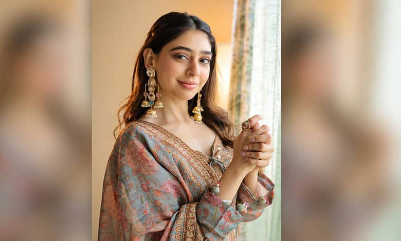 Niti Taylor wearing traditional Indian dress with jewelry, smiling softly indoors.