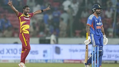 Cricket player celebrating with arms outstretched during match at the stadium.