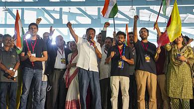 Group of people at a rally holding Indian flags and raising fists in support.