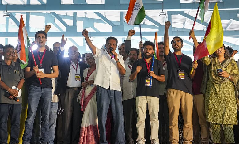 Group of people at a rally holding Indian flags and raising fists in support.