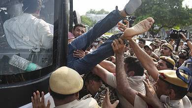 Protesters and police clash as a person is forcibly removed from a bus during a demonstration.