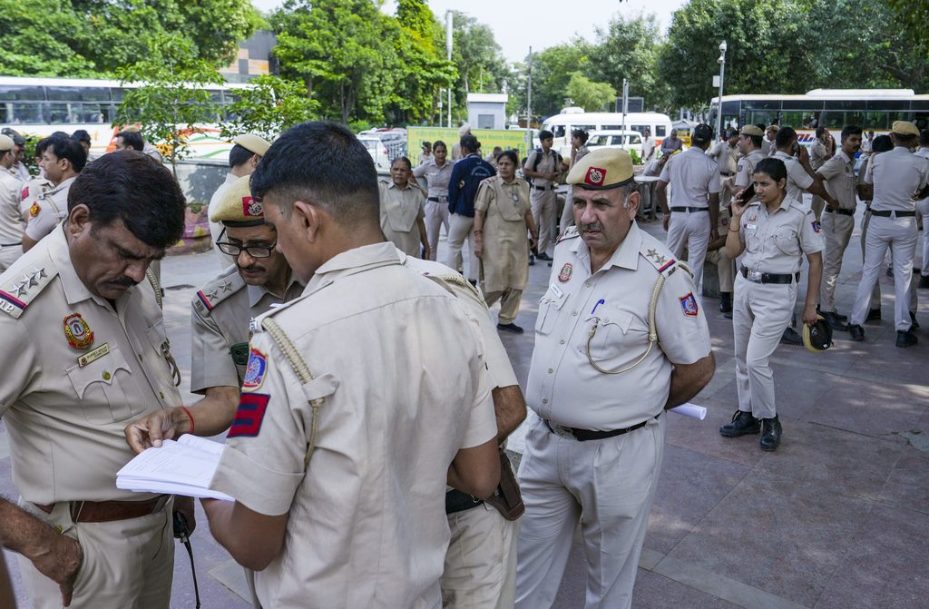 Police officers gathered at a public event, some reviewing documents, in an outdoor setting.