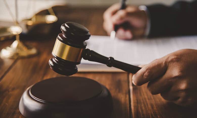 Gavel and hand of a judge in a courtroom setting, symbolising legal proceedings.
